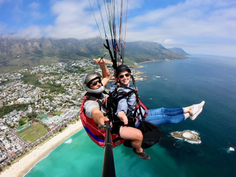 Tandem-Paragliding in Kapstadt mit Start am Lion's Head. Im Hintergrund liegt die Bergkette der 12 Apostel, unter uns die Bucht von Camps Bay.