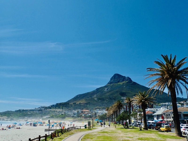 Die Strandpromenade in Camps Bay: links der Strand, in der Mitte der Lion's Head mit Paragliding-Startplatz und rechts die Restaurants an der Promenade.