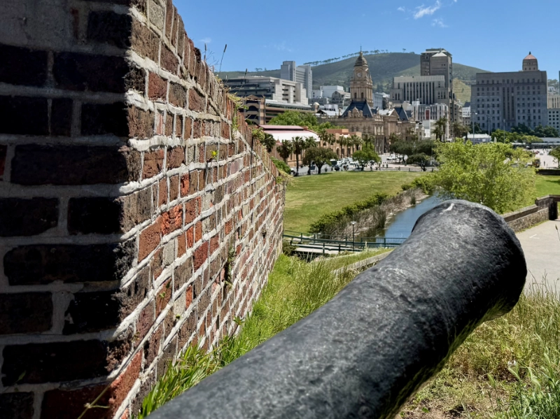 Auf dem Mauerring mit einer der alten Kanonen und Blick auf die Stadt. Im Hintergrund ist der Signal Hill zu sehen.